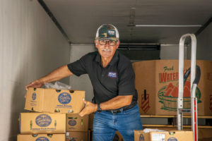 Employee unloading produce out of delivery truck.