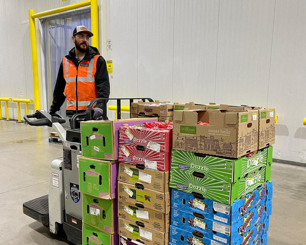 Employee loading produce on a pallet in the warehouse.